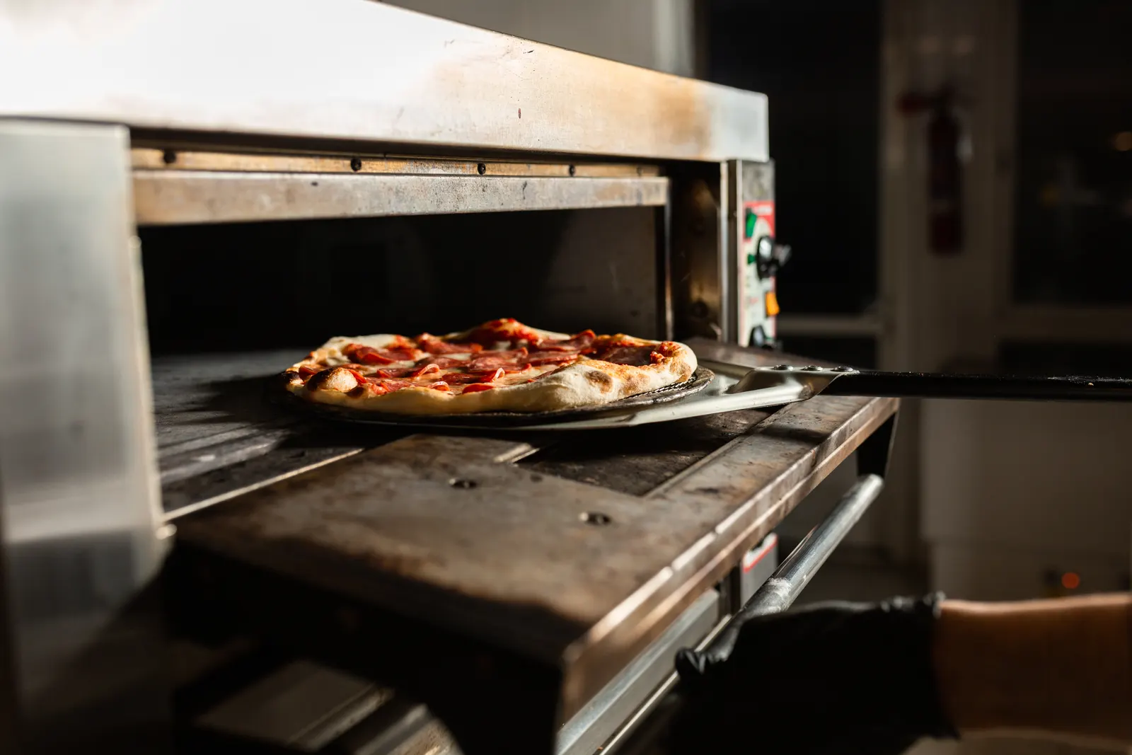 Nygräddad pepperonipizza på väg ut ur ugnen