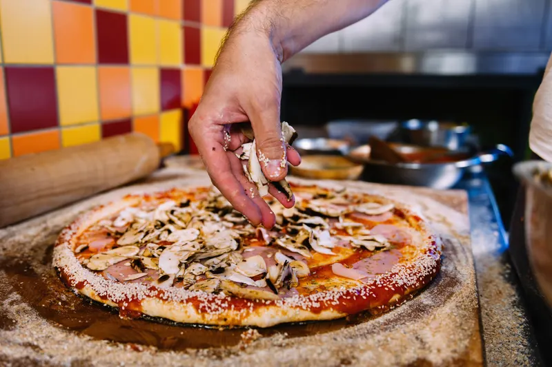 Pizza toppas med färska champinjoner