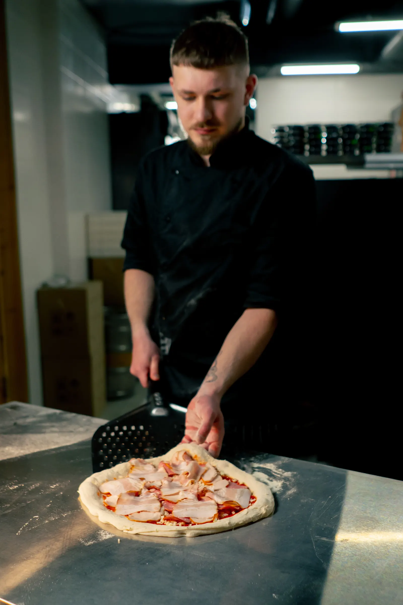 Young pizza baker working in the pizzeria kitchen
