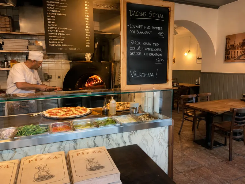 Pizzeria med vedugn, menyskyltar och pizzakartonger