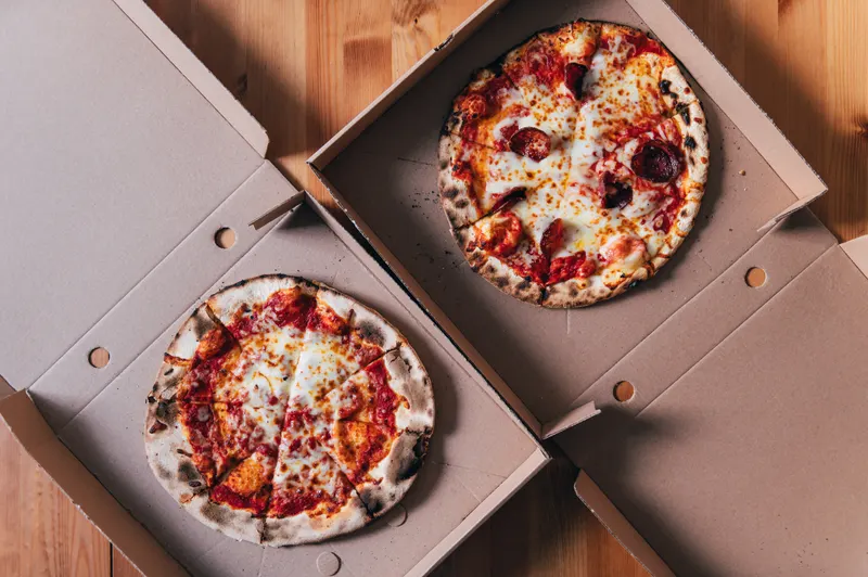 Två pizzor i kartonger redo för avhämtning